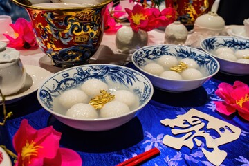 Wall Mural - Tang Yuan Dessert Table A homely table setup with bowls of sweet glutinous rice balls in a clear broth, accompanied by decorative paper cuttings of the Chinese character