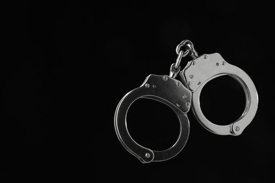 Wall Mural -  - metal chain handcuffs on black background, closeup. space for text