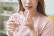 © KMPZZZ - Dietary supplement, healthy diet positive asian young woman hand holding pill capsule, take vitamin in mouth for beauty skin hair, taking medicine with glass of water at home, pharmacy and health care