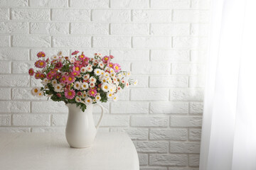 Wall Mural - Vase with beautiful flowers on wooden table near white brick wall. Space for text