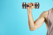 © New Africa - Man exercising with dumbbell on light blue background, closeup. Space for text