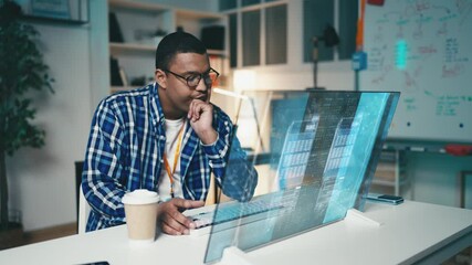 Focused IT developer works with programming code on a futuristic computer screen