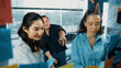 © Summit Art Creations - Portrait of professional diverse business team brainstorming marketing idea on colorful sticky notes stuck on glass board. Hispanic project manager write business strategy on note. Manipulator.