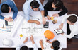 © InfiniteFlow - Top view banner of diverse group of civil engineer and client working together on architectural project, reviewing construction plan and building blueprint at meeting table. Prudent