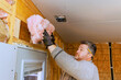© ungvar - Skilled individual installs pink insulation into wall cavities while preparing space for improved energy efficiency.