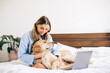 © Maria Vitkovska - Smiling woman working from home with her golden retriever dog