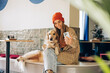 © Maria Vitkovska - Young woman taking selfie with golden retriever in modern cafe