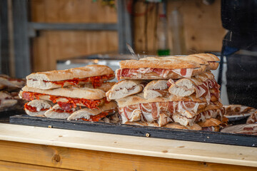 Canvas Print - Freshly made sandwiches featuring iberian ham are stacked and ready to be enjoyed at a bustling market stall