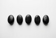 © LTh - Five black stones arranged in a row on a white background