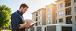 © Anastasiya - Maintenance worker evaluating property in front of apartment buildings