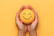 © Ranazain - Hands Holding Smiley Face Stress Ball on Yellow Background