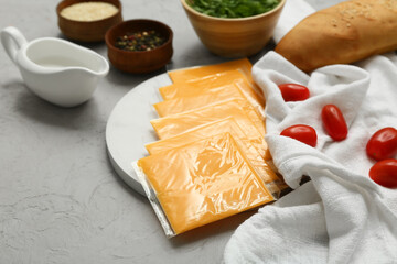 Wall Mural - Plate with slices of delicious processed cheese, tomatoes and bread on grey grunge table