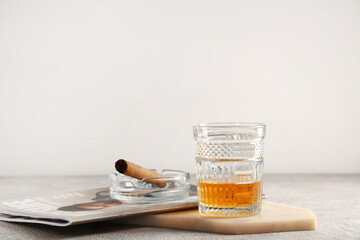 Wall Mural - Glass of cold rum, cigar and magazine on table against grey background. Closeup