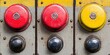 © HoursStudio - This image features three colorful buttons-two red and one yellow-mounted on a metallic surface, showcasing a vintage industrial design.