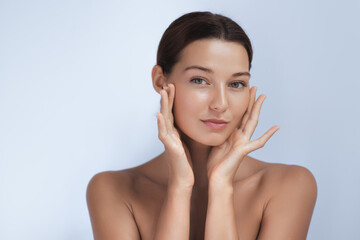 a young woman with flawless, glowing skin gently touches her face, radiating natural beauty and soft