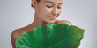 © Buyanskyy Production - A young woman with flawless, radiant skin gently holding a large green leaf, symbolizing natural skincare. Perfect for beauty, wellness, and eco-friendly cosmetic promotions.
