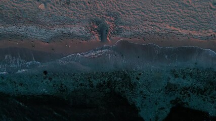 Canvas Print - Drone view of sea water with gentle waves hitting the sandy beach in a tranquil moment at sunset