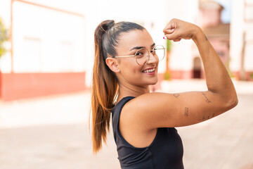 Wall Mural - Young pretty woman at outdoors With glasses and celebrating a victory