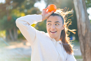 Wall Mural - Young pretty brunette woman holding an orange