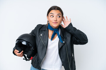 Poster - Young caucasian woman with a motorcycle helmet isolated on blue background listening to something by putting hand on the ear