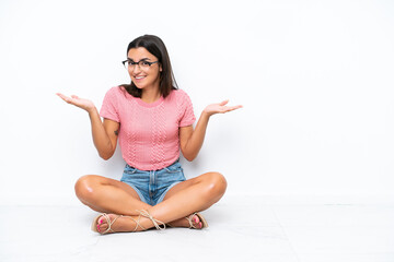 Wall Mural - Young caucasian woman sitting on the floor isolated on white background with shocked facial expression