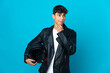 © luismolinero - Young man with a motorcycle helmet over isolated blue background having doubts and thinking