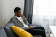 © satura_ - Cheerful curly haired ethnic african american male in casual clothes resting at home on comfortable sofa while watching tv channels or movie during weekend. Tv set, online television and entertiment