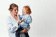 © SHOTPRIME STUDIO - Mother and child embracing with joy and love in a white background, beauty of motherhood celebrated