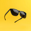 © southwind - Black sunglasses floating on vibrant yellow background: summer fashion eyewear