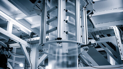 Poster - Automatic polyethylene plastic bag production machine with lighting effect. Close-up of the roller of the plastic bag production machine in the light blue scene. product packaging concept