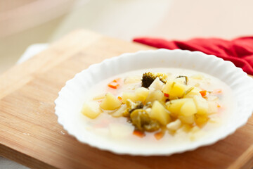 Wall Mural - Creamy vegetable soup in a white bowl, served on a wooden board.  Perfect for a light and healthy meal.