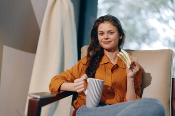 Canvas Print - Young woman enjoying a healthy snack with a cup of tea, showcasing a relaxed mood in a cozy indoor setting Healthy eating, lifestyle, comfort, and well being are highlighted