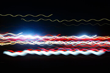 Wall Mural - Abstract blurred colorful light effect on a black background. Long exposure photo of moving camera.