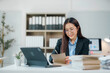 © Crystal - Asian businesswoman working with documents and using tablet in office