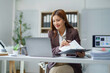 © Crystal - Asian businesswoman working with documents and using laptop in office