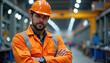 © Xenia - Determined factory worker in an orange safety outfit posing confidently in an energetic warehouse environment, symbolizing hard work and dedication.