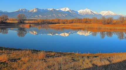 Wall Mural - Autumn lake reflecting snow-capped mountains at sunrise