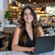 © SECOND - Smiling woman works on laptop in cafe