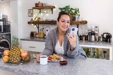 Wall Mural - young latin woman plus size using mobile phone in kitchen at home in Mexico Latin America, hispanic overweight female 	