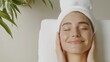 © Y_Malashkevych - A happy young woman relaxes while receiving a facial massage in a minimalist spa setting. Her radiant skin glows under soft lighting contributing to a tranquil atmosphere