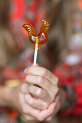 Lollipop shaped like a cockerel. An element of Russian folklore.A child's hands hold a lollipop in close-up