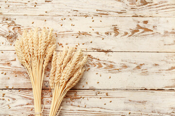 Wall Mural - Bundle of wheat ears and grains on white wooden table