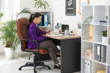 Sticker - Female office worker with mobile phone doing paper work on armchair at workplace in office