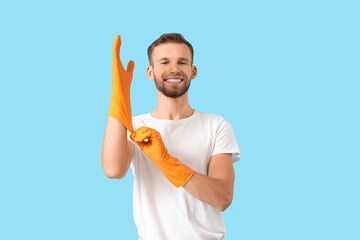 Canvas Print - Male janitor wearing rubber gloves on blue background