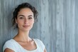 © YouraPechkin - Woman with natural beauty poses against a textured gray wall in a soft, casual outfit