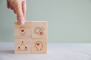 hands holding wooden cube blocks with wellness icons, positive mental health, life balance concept
