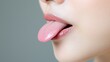 © BROPRADANA - Woman's mouth, tongue out, close-up, grey background, beauty