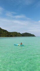 Wall Mural - Explore the serene beauty of Koh Kradan Island as a lone kayaker glides over the turquoise waters. Experience the tranquility and stunning landscapes that make this destination paradise.