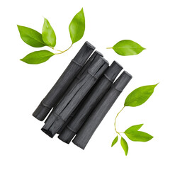 Fototapete - A visually appealing arrangement of dark charcoal sticks and vibrant green leaves against a black background.