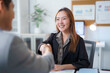 © amnaj - Smiling businesswoman shaking hands with businessman at office desk
